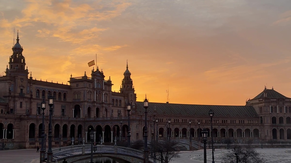 Plaza de España de Sevilla al atardecer, con el cielo anaranjado sobre el edificio central